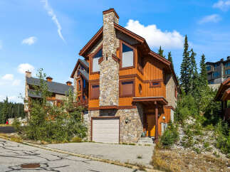 Experience mountain living in this stunning timber-framed home, featuring a grand stone chimney and warm wood siding.