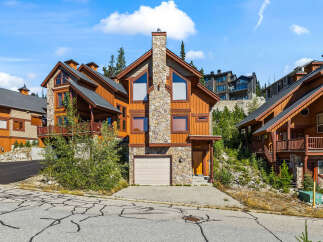 Experience luxury mountain living in this stunning timber-frame home, boasting a striking stone chimney and expansive windows that capture breathtaking views.