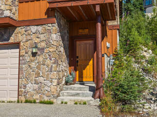 Discover this charming mountain home featuring a rustic stone facade and a warm, inviting wooden door.
