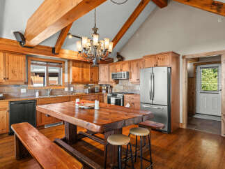 Experience rustic charm in this spacious kitchen featuring beautiful knotty pine cabinetry and exposed wooden beams.