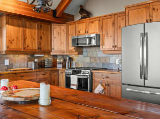 Experience rustic charm in this spacious kitchen featuring warm, knotty pine cabinetry and a durable slate tile backsplash.