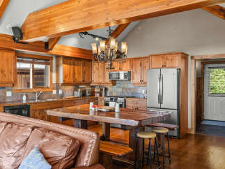 Experience rustic charm in this spacious kitchen and living area, featuring warm wooden cabinetry and exposed beams.