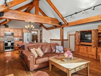 Experience rustic charm in this spacious living area, featuring exposed wooden beams and a cozy leather sofa perfect for relaxing.