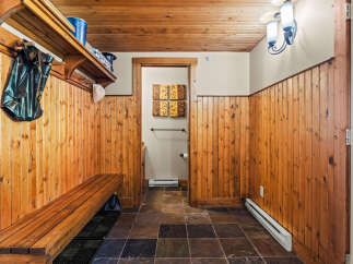 Step into this charming entryway featuring warm wood paneling and a rustic wooden bench, perfect for removing shoes after a day outdoors.