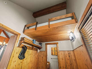 Experience rustic charm in this unique loft bedroom, featuring a cozy wooden bunk bed suspended from the ceiling.