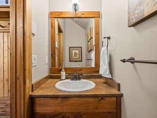 This charming bathroom features a rustic wooden vanity with a warm-toned countertop and a white undermount sink.