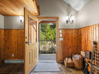 Step into this charming entryway featuring warm wood paneling and a vaulted cedar ceiling, creating a cozy and inviting atmosphere.