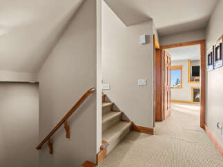 This image showcases a charming interior hallway with a carpeted staircase and a wooden handrail.