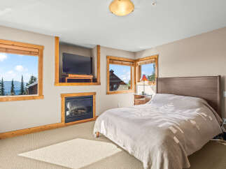 Experience ultimate comfort in this cozy bedroom, featuring a warm fireplace and a large television for entertainment.