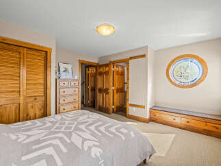 This charming bedroom features a cozy bed with a patterned blanket, complemented by a wooden dresser and ample closet space.