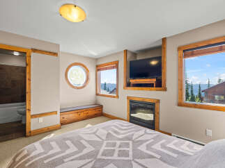 Experience ultimate comfort in this master suite, featuring a cozy fireplace and a mounted television for entertainment.