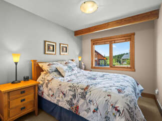Experience cozy mountain living in this charming bedroom, featuring a comfortable queen-size bed adorned with a whimsical ski-themed comforter.