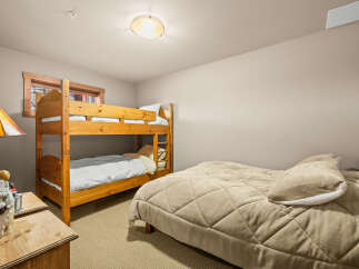 This cozy bedroom features a space-saving bunk bed and a comfortable queen-sized bed, perfect for accommodating family or guests.