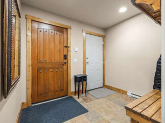 Step into a welcoming entryway featuring a rustic wooden door with decorative studs and a modern black lock system.