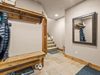 Welcome guests into this charming entryway featuring a rustic wooden bench and coat rack, perfect for storing winter gear.