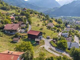 Nestled on a lush green hillside, this property offers breathtaking panoramic views of a charming village and majestic mountains.