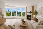 Experience breathtaking city and water views from this stunning living room, featuring a modern gas fireplace and elegant wood-slat accent wall.
