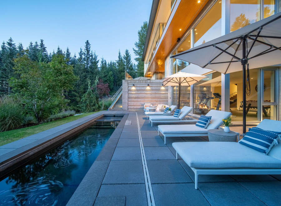 Experience luxury outdoor living with this stunning property featuring a sleek infinity pool and ample lounge seating.