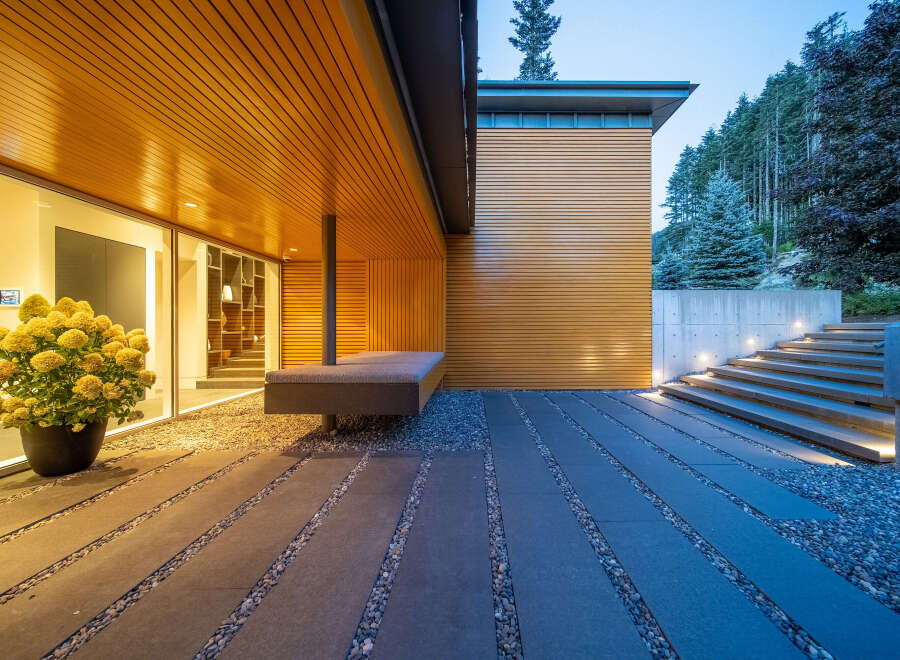 Experience modern luxury with this stunning architectural home featuring sleek wood paneling and expansive glass windows.