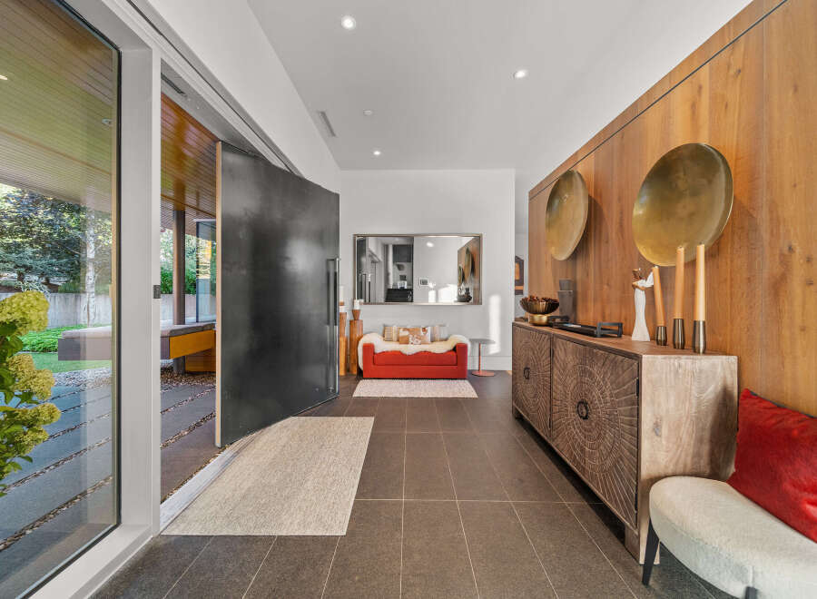 Step into a modern entryway featuring a striking oversized pivot door and sleek tile flooring.