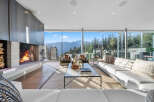 Experience breathtaking mountain views from this modern living room, featuring a striking concrete fireplace and expansive floor-to-ceiling windows.