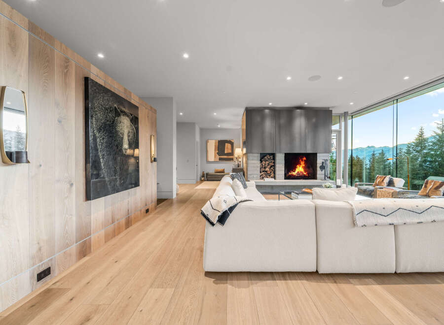 Experience luxury living in this stunning modern home, featuring a spacious open-concept living area with a cozy fireplace and breathtaking mountain views through expansive windows.