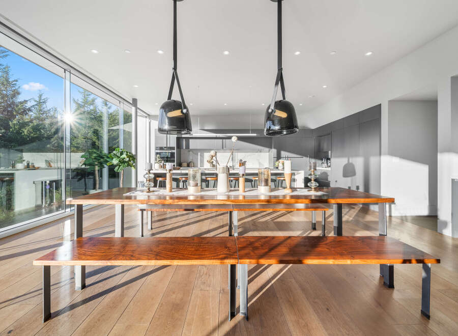 Experience modern living in this stunning home featuring a spacious open-concept dining area with a beautiful live-edge wood table and benches.