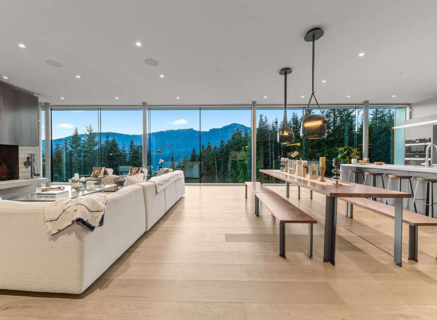 Experience breathtaking mountain views from this stunning modern living space, featuring a cozy fireplace and expansive floor-to-ceiling windows.