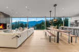 Experience breathtaking mountain views from this stunning modern living space, featuring a cozy fireplace and expansive floor-to-ceiling windows.