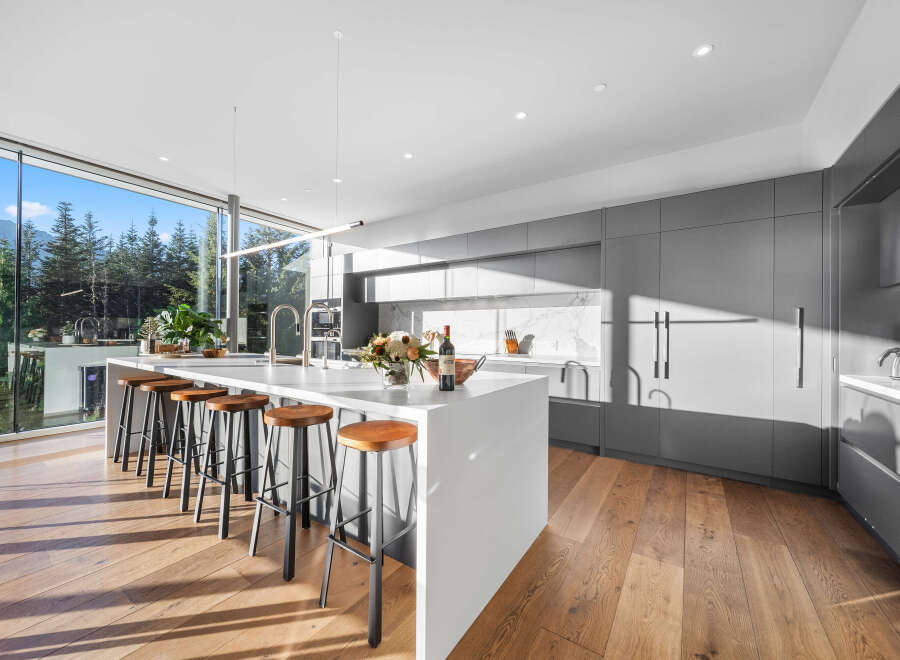 Experience modern luxury in this stunning kitchen featuring a large waterfall island with bar seating, perfect for entertaining.