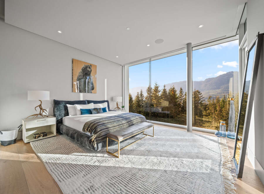 Experience luxury mountain living in this stunning bedroom featuring a king-sized bed with plush bedding and a cozy throw.