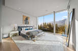 Experience luxury mountain living in this stunning bedroom featuring a king-sized bed with plush bedding and a cozy throw.
