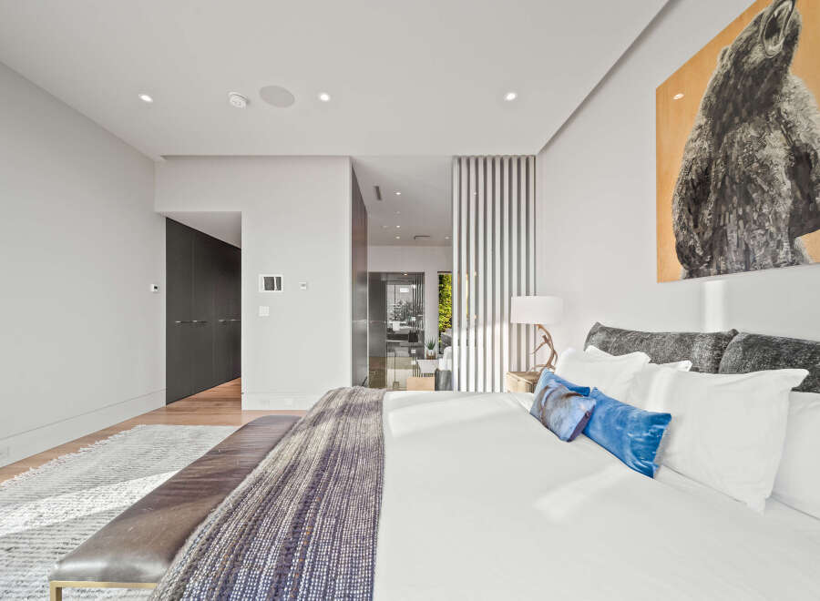 Experience luxury in this master suite, featuring a king-sized bed adorned with plush pillows and a striking bear artwork above.