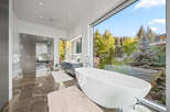 Experience luxury in this modern bathroom featuring a stunning freestanding bathtub with a panoramic view of the lush, green outdoors.