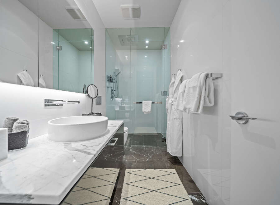 Experience modern luxury in this stunning bathroom featuring a sleek vessel sink atop a marble vanity.