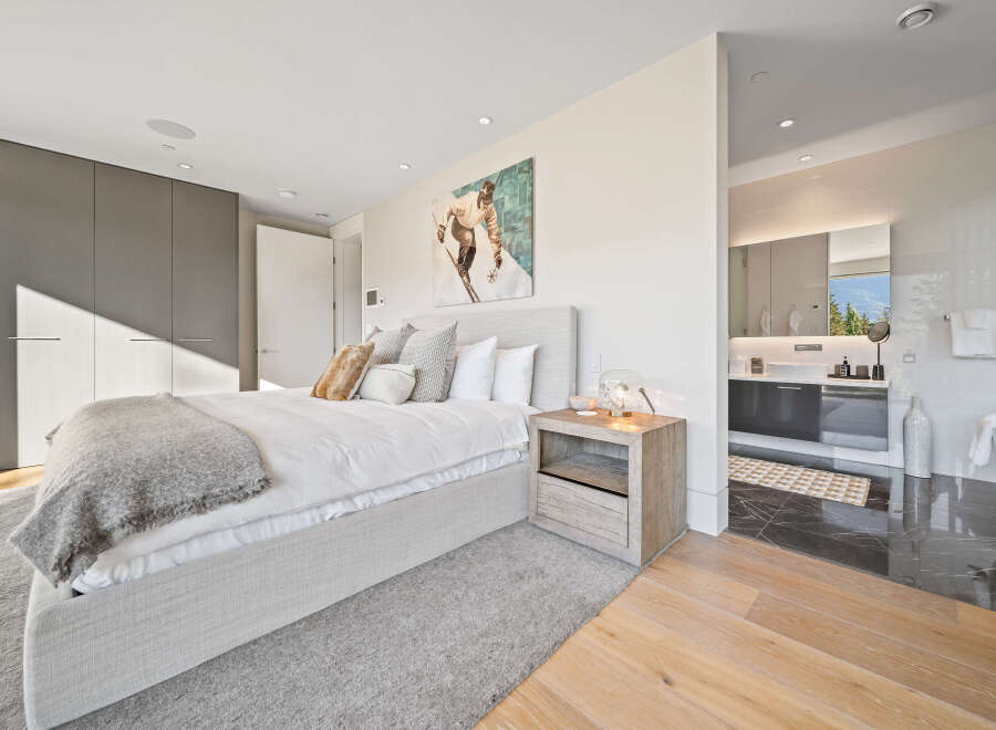 Experience luxury living in this master suite, featuring a king-sized bed with plush bedding and a striking ski-themed artwork above.