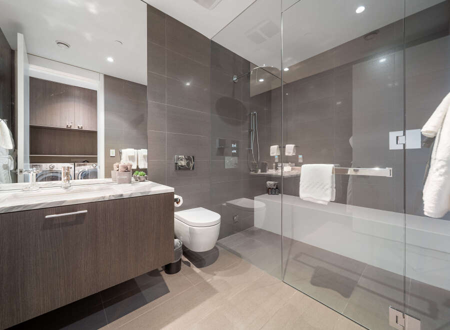 Experience modern luxury in this stunning bathroom featuring a sleek vanity with a marble countertop and a spacious glass-enclosed shower.
