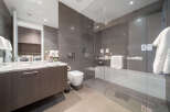 Experience modern luxury in this stunning bathroom featuring a sleek vanity with a marble countertop and a spacious glass-enclosed shower.