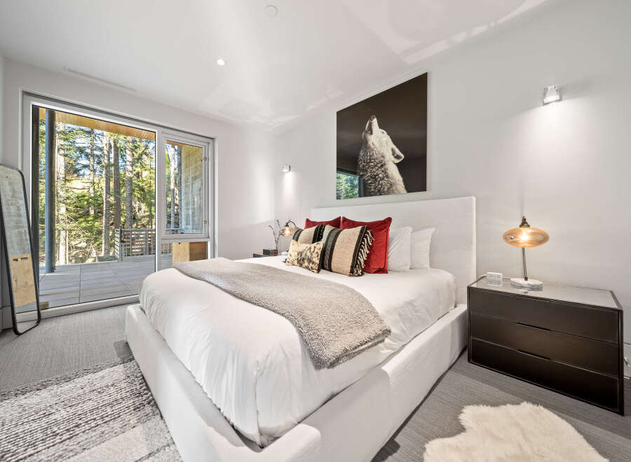 Experience modern luxury in this serene bedroom, featuring a plush king-sized bed adorned with decorative pillows and a cozy throw.