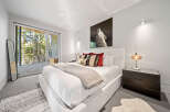 Experience modern luxury in this serene bedroom, featuring a plush king-sized bed adorned with decorative pillows and a cozy throw.