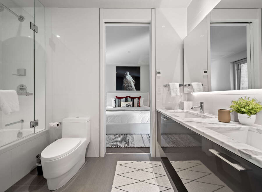 Experience modern luxury in this stunning bathroom featuring a sleek bathtub and shower combination, complemented by a pristine white toilet.