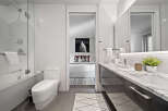 Experience modern luxury in this stunning bathroom featuring a sleek bathtub and shower combination, complemented by a pristine white toilet.