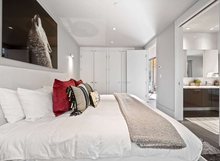 Experience modern luxury in this stunning bedroom featuring a plush king-sized bed adorned with decorative pillows and a cozy throw blanket.