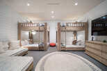 This spacious bedroom is designed for comfort and fun, featuring two sets of twin bunk beds with natural wood finishes and crisp white linens.