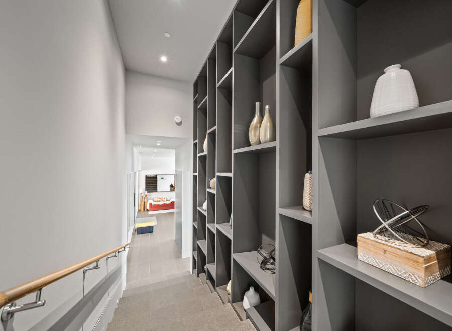 This modern hallway features a sleek gray built-in shelving unit, perfect for displaying decorative items.