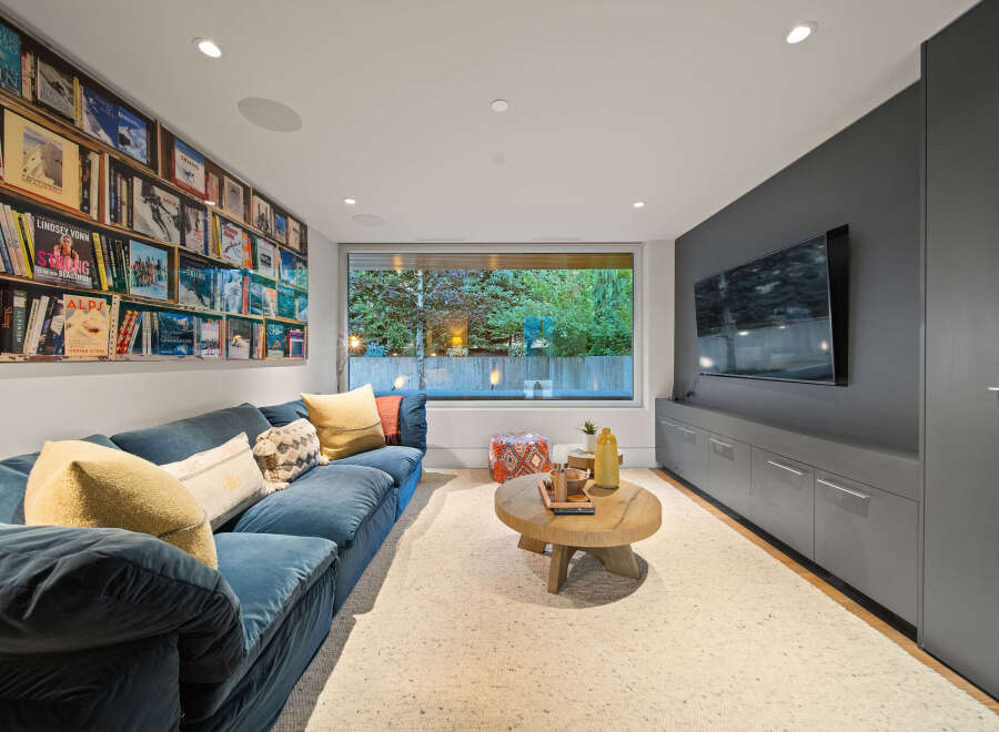 This cozy living room features a plush blue sectional sofa perfect for relaxing, complemented by a unique wall of books showcasing ski and mountaineering themes.