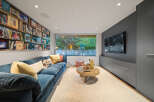 This cozy living room features a plush blue sectional sofa perfect for relaxing, complemented by a unique wall of books showcasing ski and mountaineering themes.
