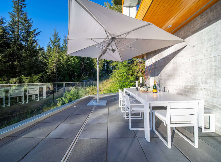 Enjoy al fresco dining on this spacious patio, complete with a modern white dining set and a large cantilever umbrella for shade.