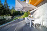 Enjoy al fresco dining on this spacious patio, complete with a modern white dining set and a large cantilever umbrella for shade.