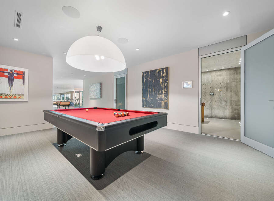 Experience ultimate entertainment in this modern game room, featuring a sleek pool table with a vibrant red felt.
